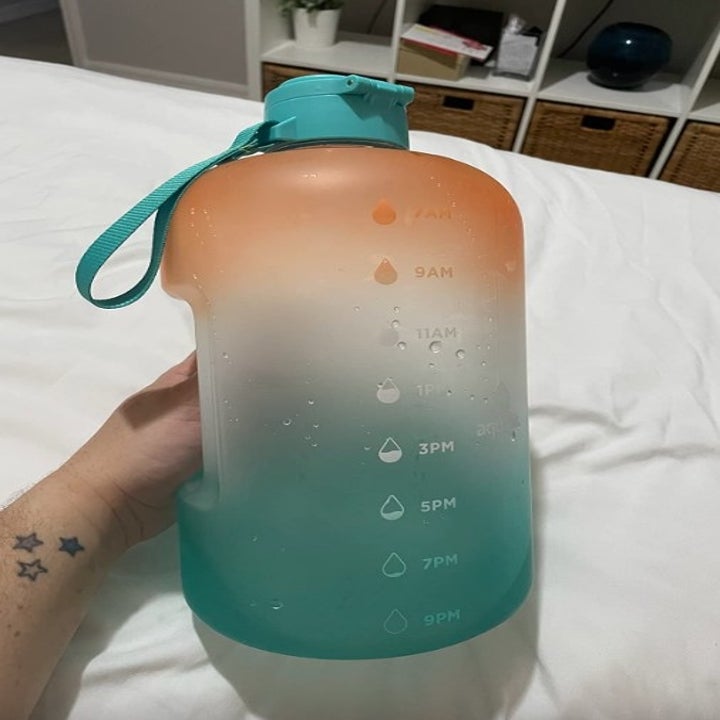 Reviewer holding ombre green and orange water bottle