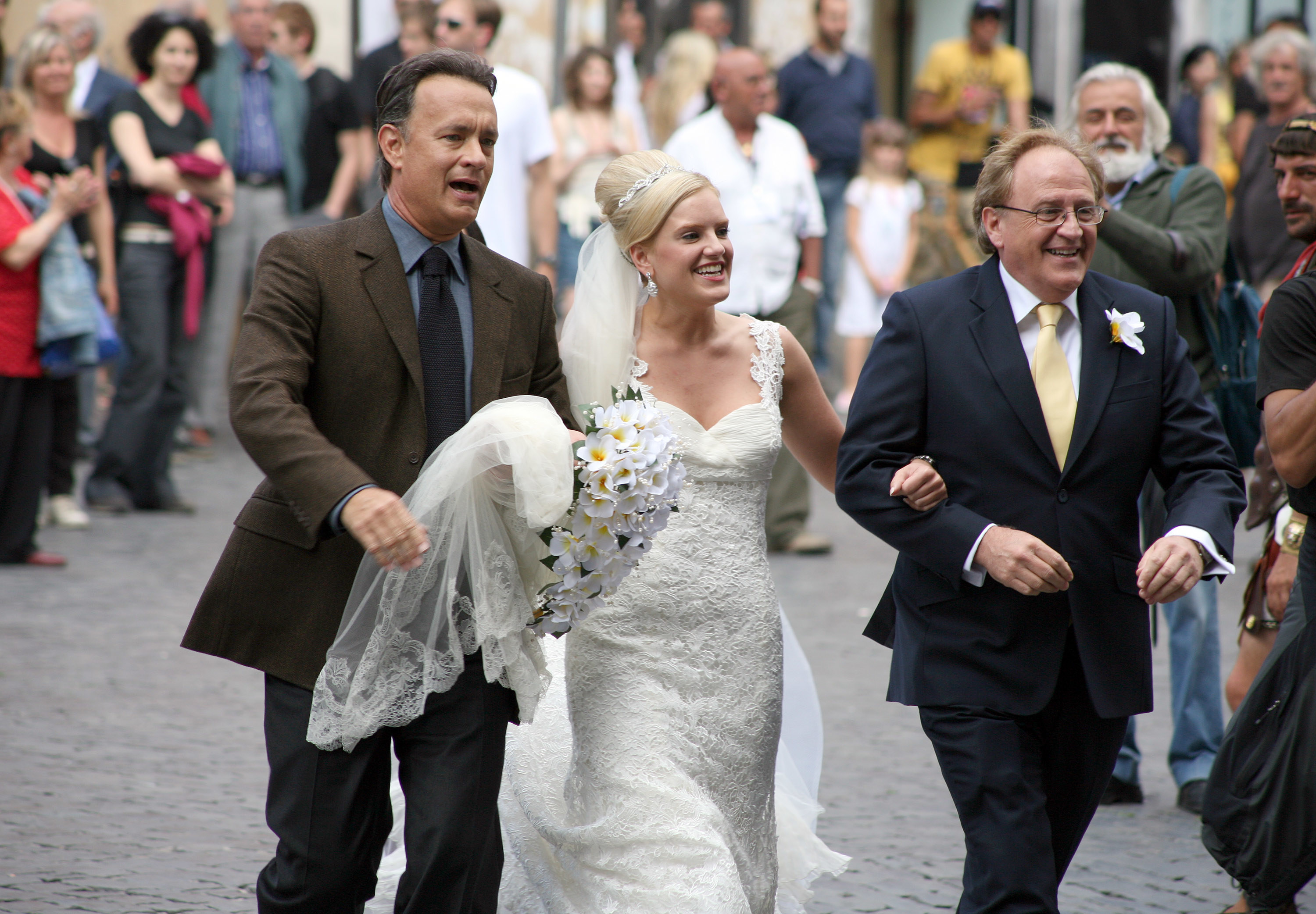 Tom links arms with a bride and her dad while walking in Rome