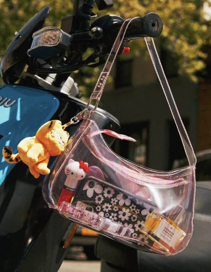 The purse filled with stuff hanging off of the handlebar of a vespa