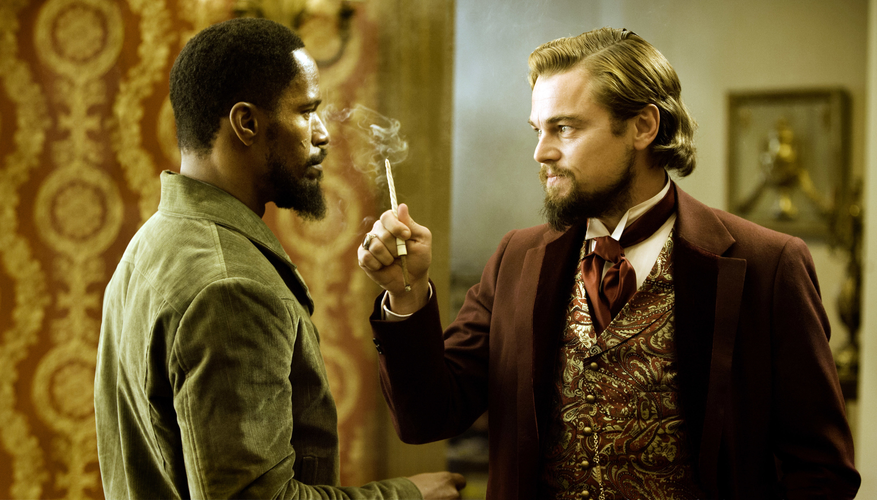 Django Unchained: A man holds a smoking cigarette threateningly in front of another man&#x27;s face