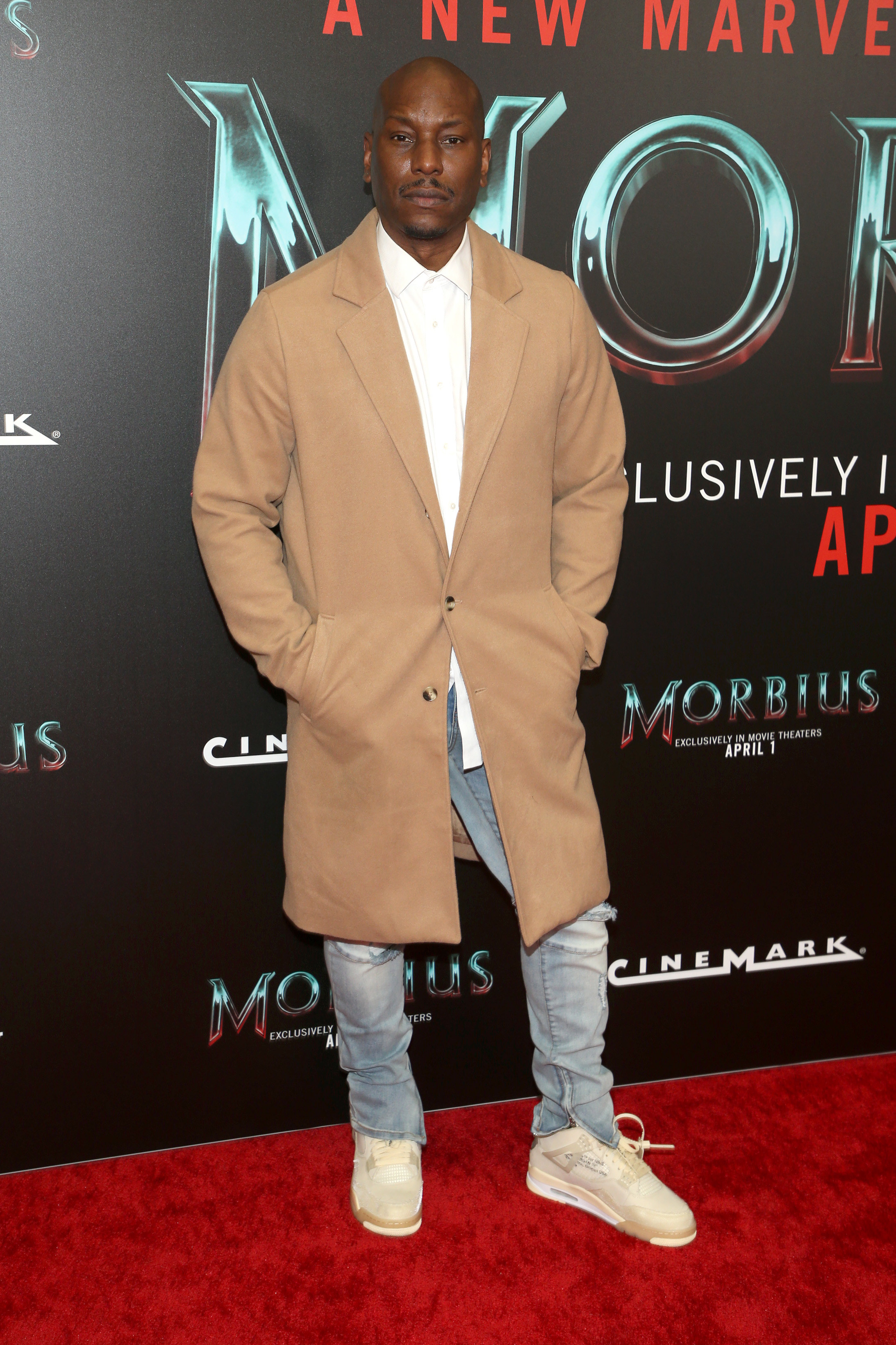 Wearing jeans and sneakers and an overcoat on the red carpet and not smiling