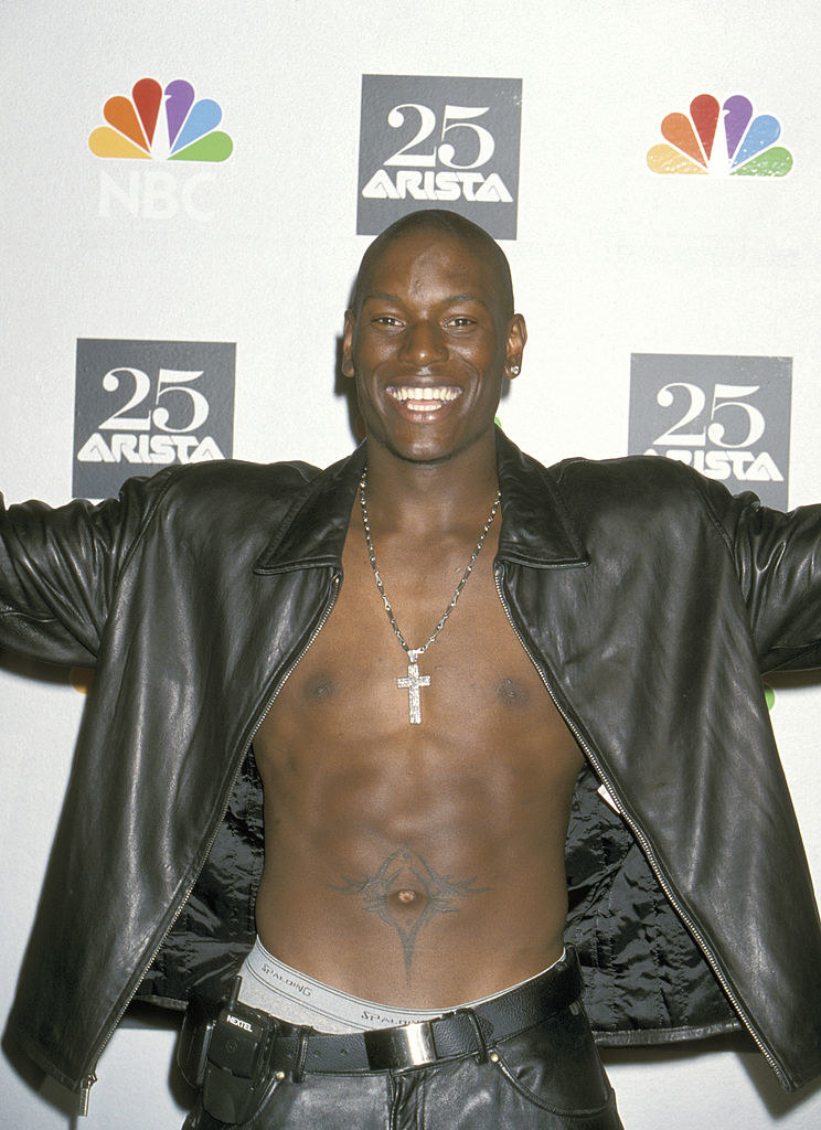 A smiling, shirtless Tyrese wearing an open leather jacket