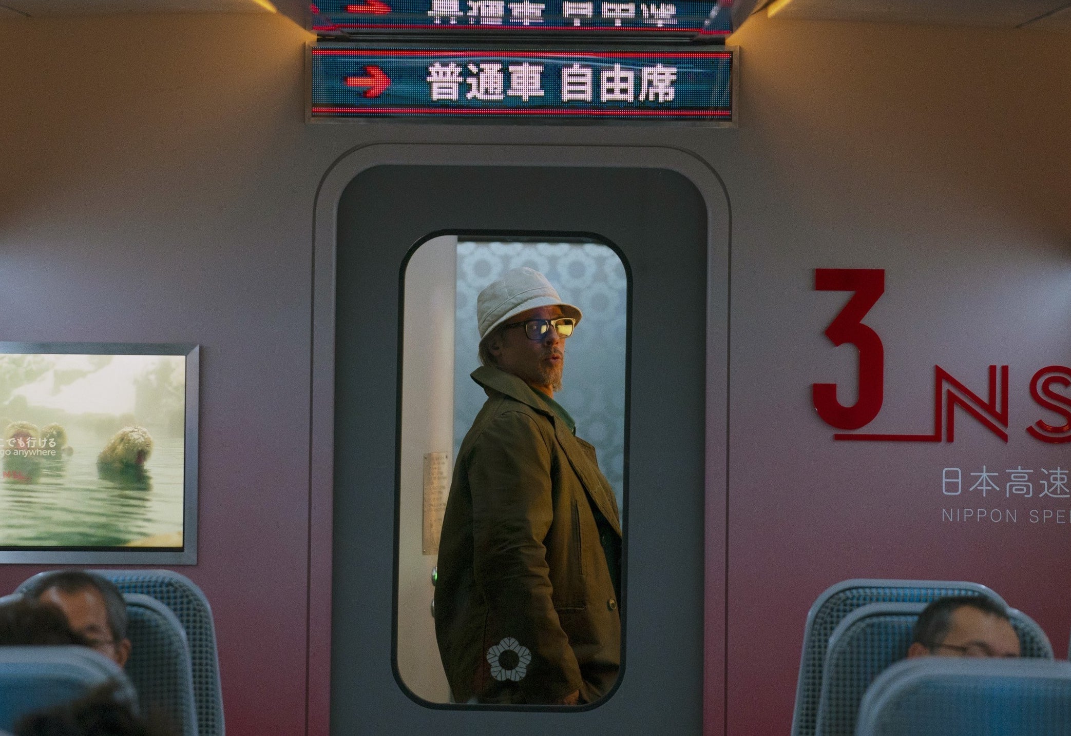 Brad wears a bucket hat and stand in a door frame on a train in the movie