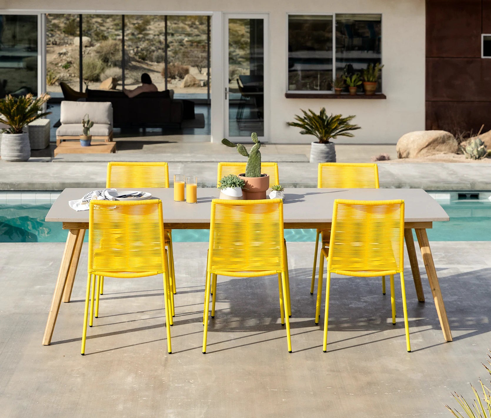 an outdoor dining table with six yellow woven chairs