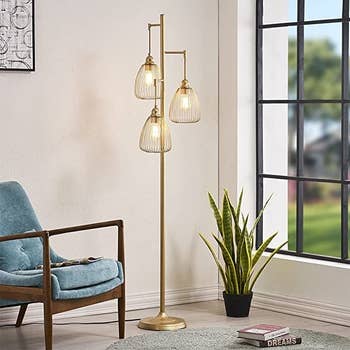 the floor lamp in a living room next to a window and chair and plant