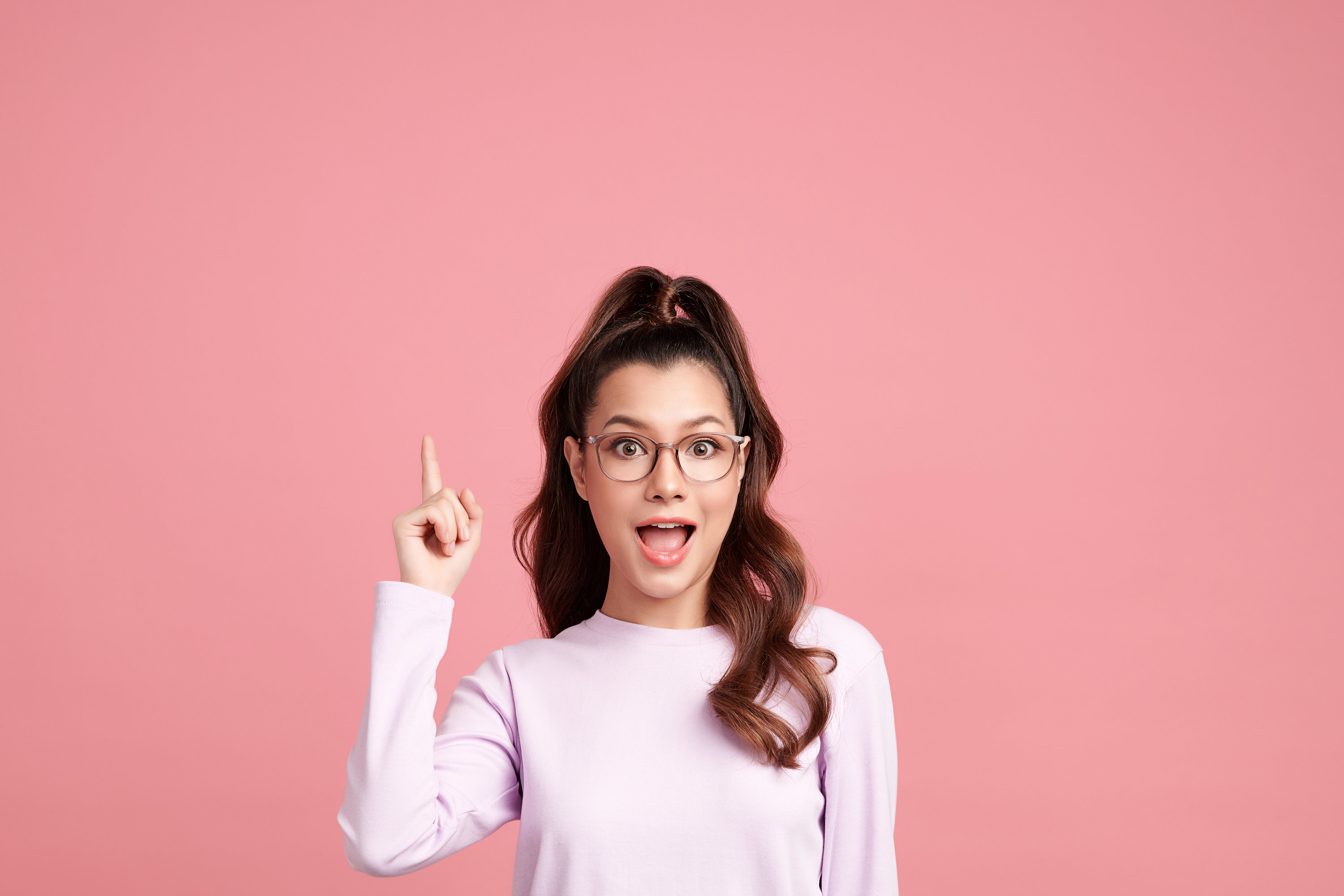 Excited young woman pointing finger up
