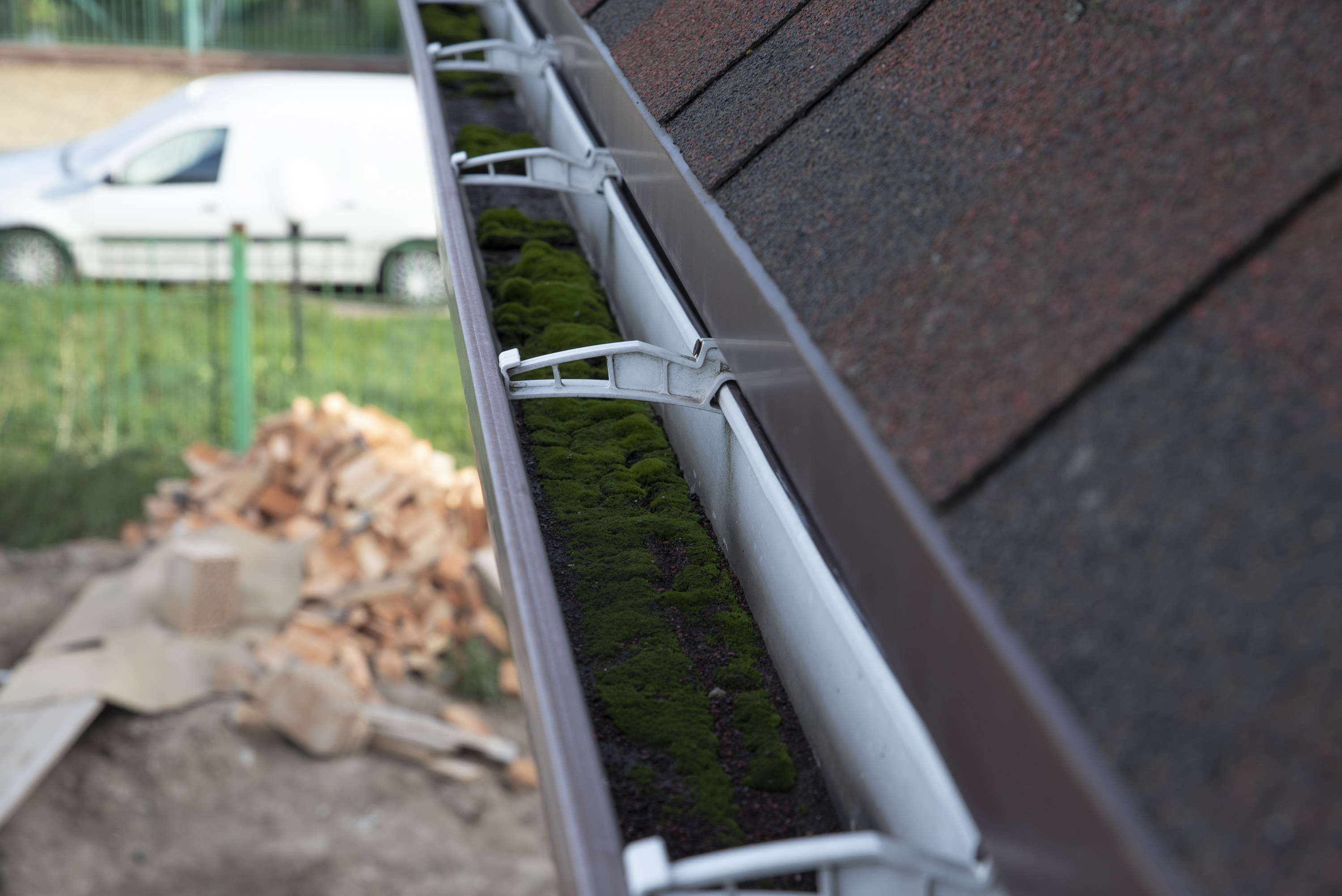 Gutter system clogged with dirt and moss