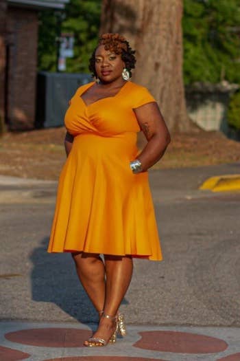 a reviewer wearing the dress in orange