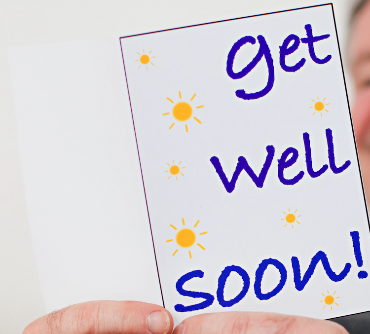 Close-up of a hand holding a &quot;Get well soon&quot; card