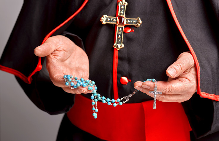 A priest holding rosary beads