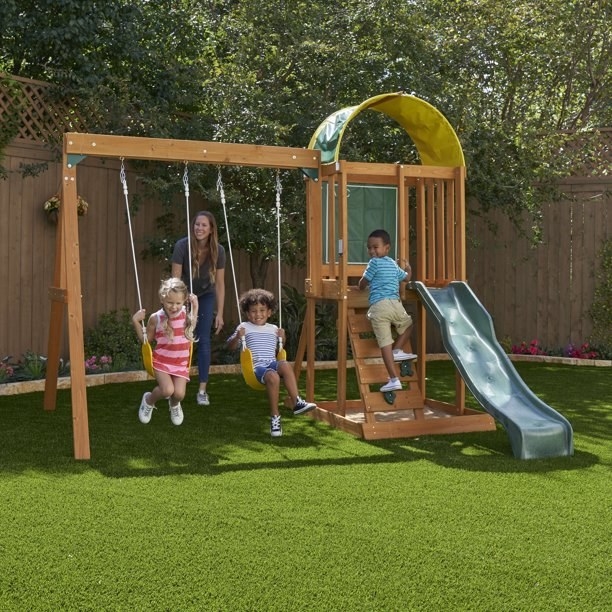 Children play on the playset while an adult supervises
