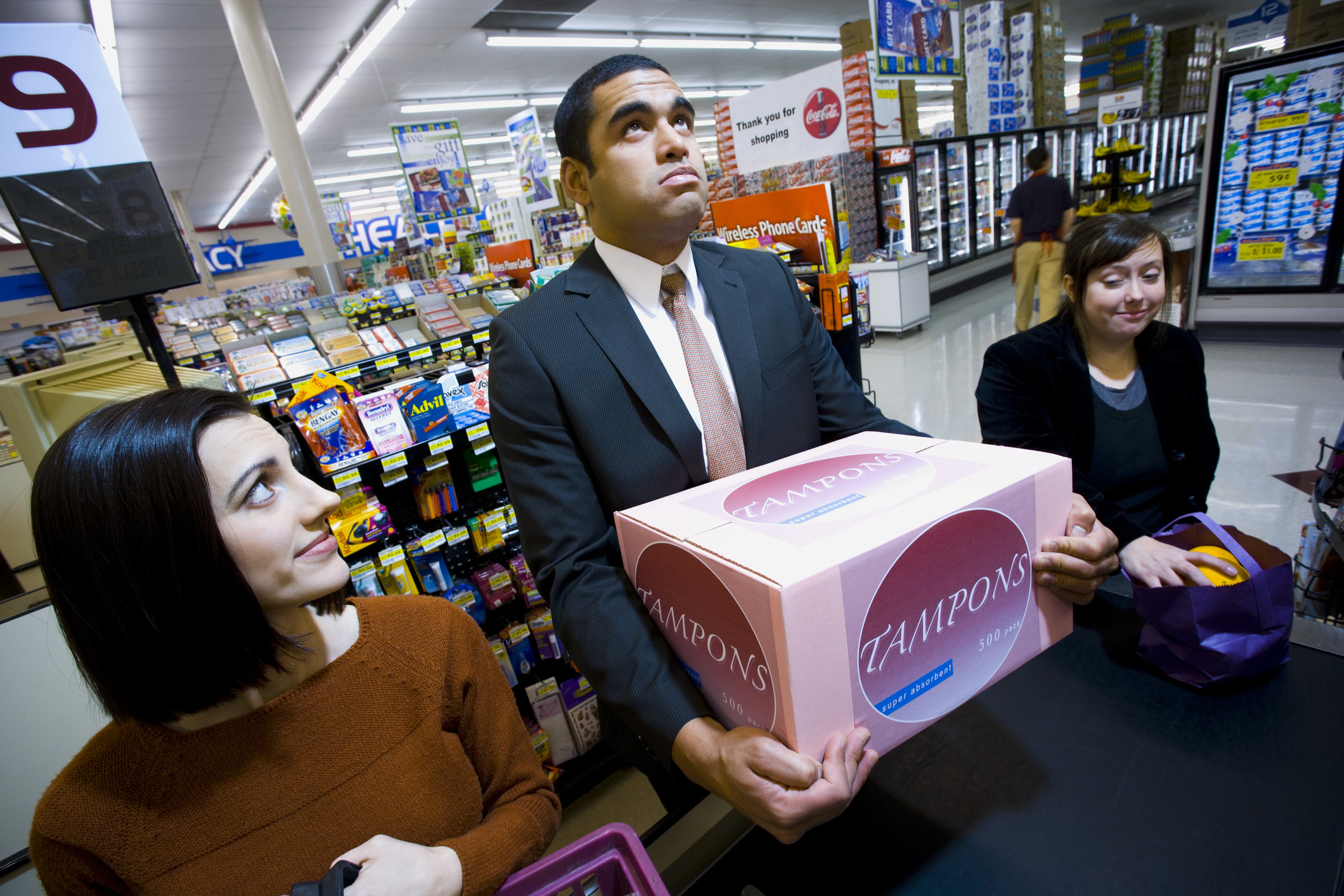 Man at the grocery checkout with a huge box of tampons
