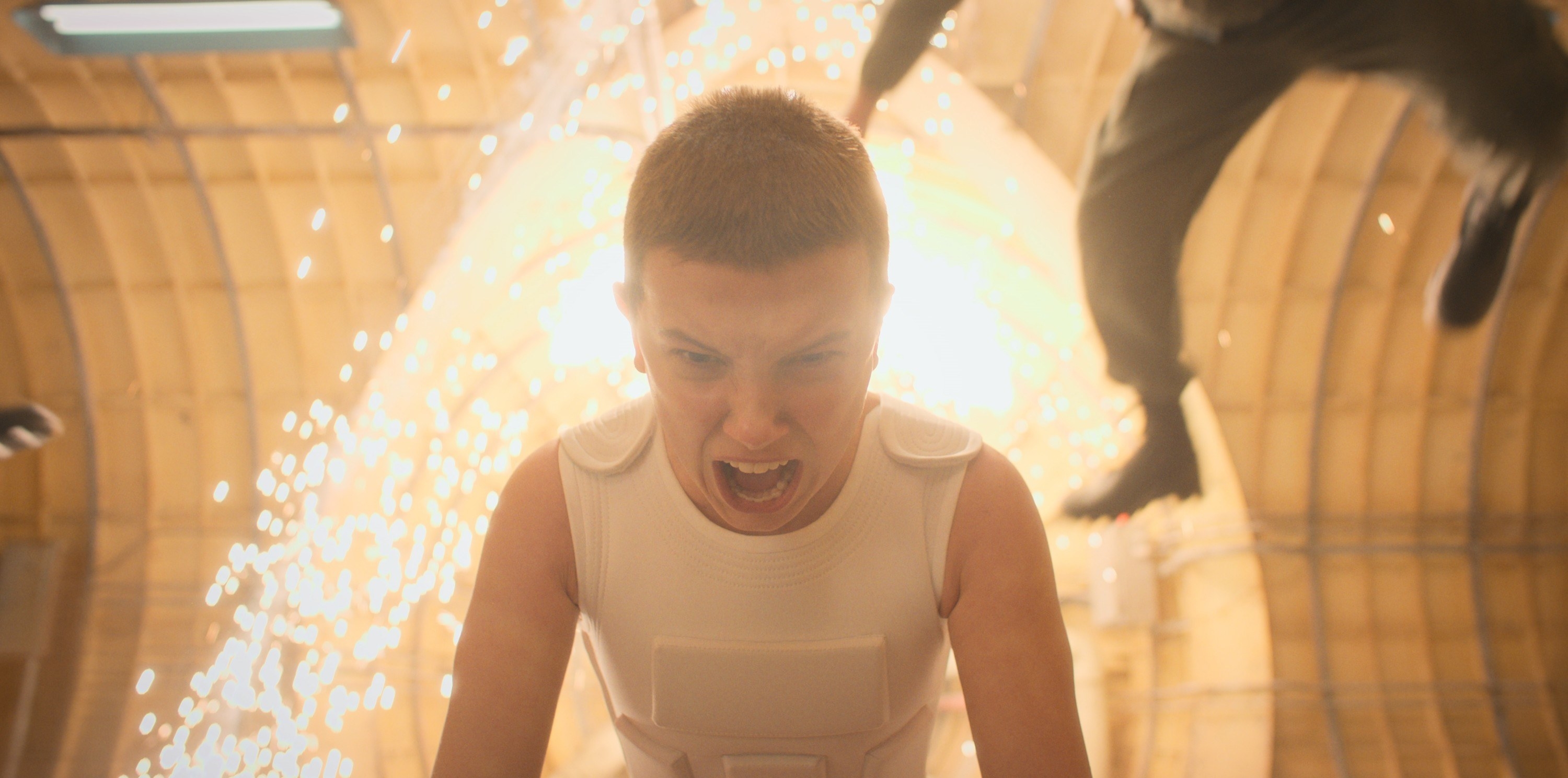 eleven standing in front of a bright light screaming while using her powers