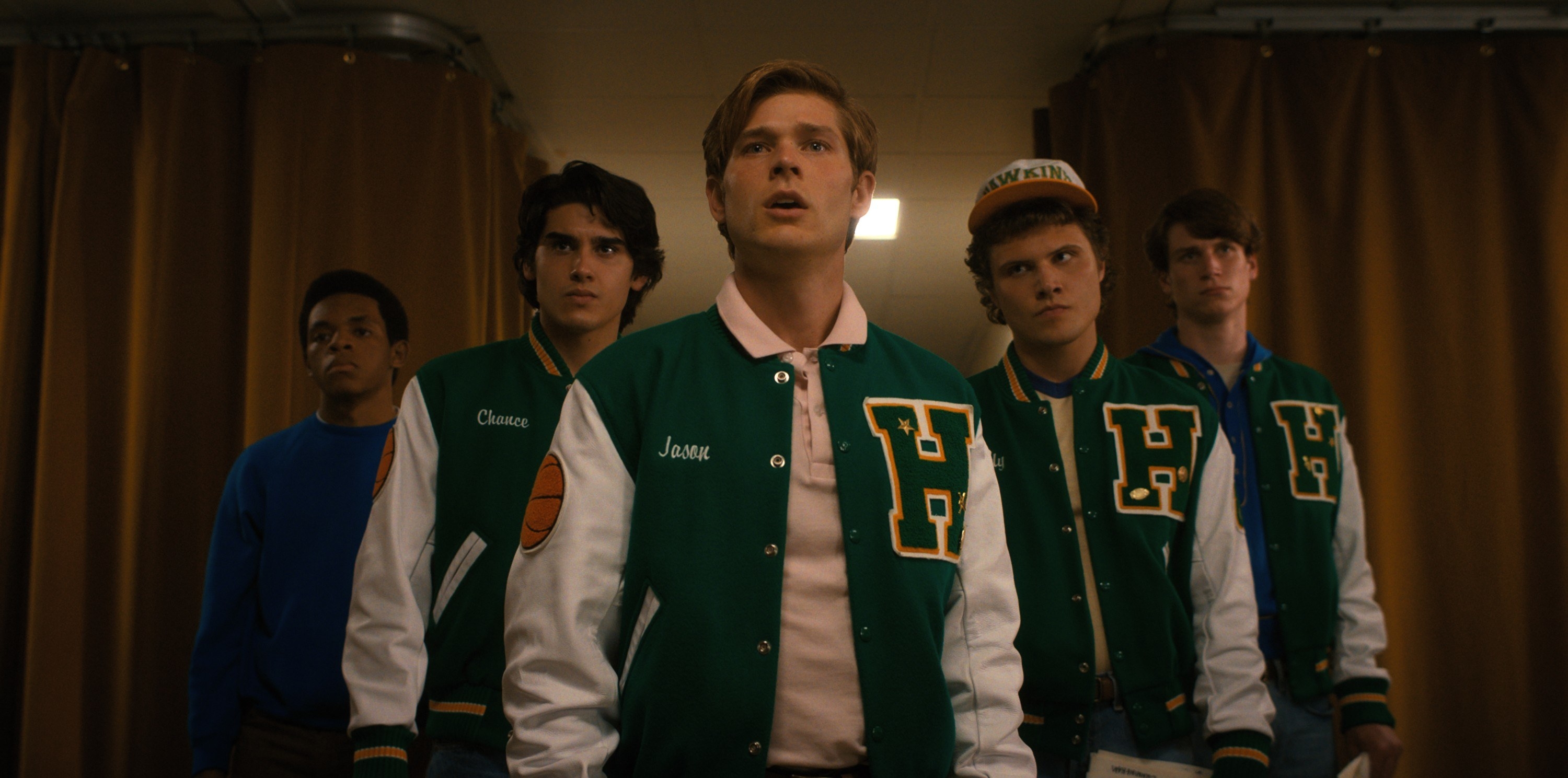 group of teen boys wearing matching letterman jackets