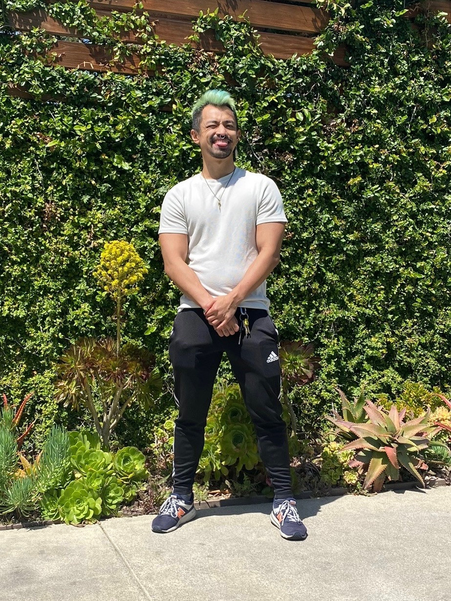 James Liang stands against a wall of plants