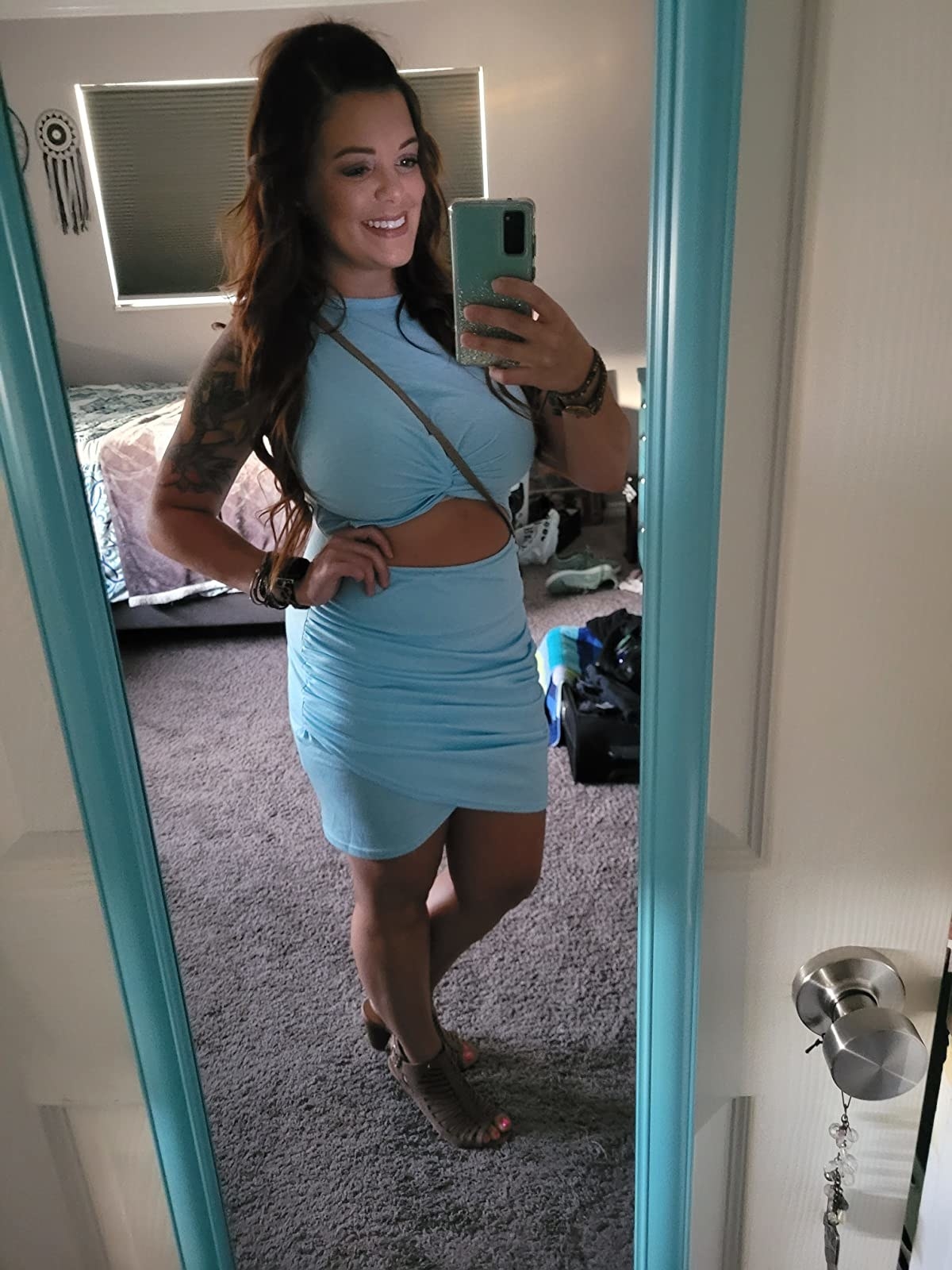 Reviewer wearing sleeveless blue mini dress with middle cut-out