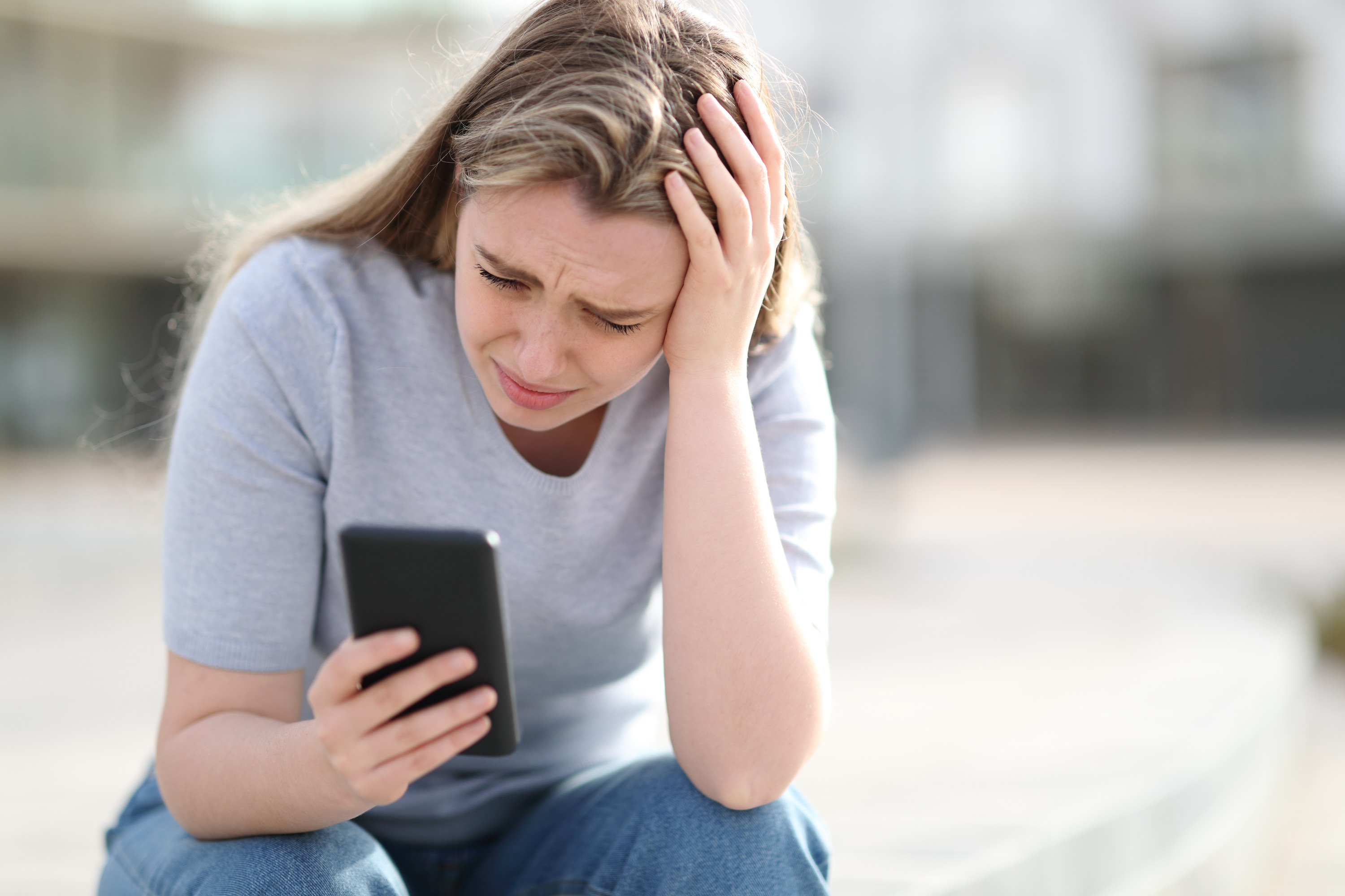 A woman squints while looking at her phone.