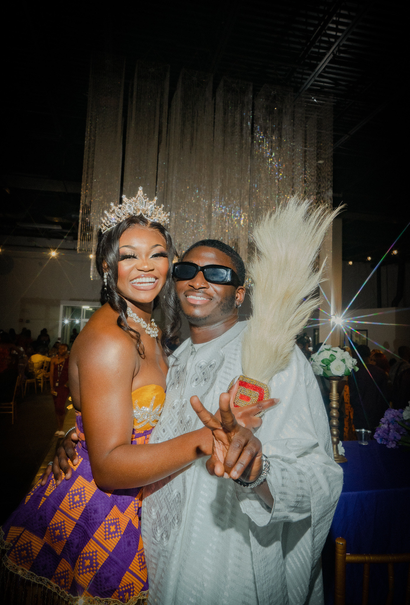 A woman and man dressed in festive Ghaniana and Nigerian attire smile at the camera 