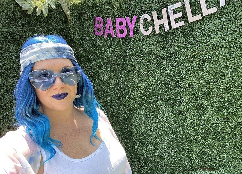 A reviewer with blue hair, blue sunglasses and blue head scarf