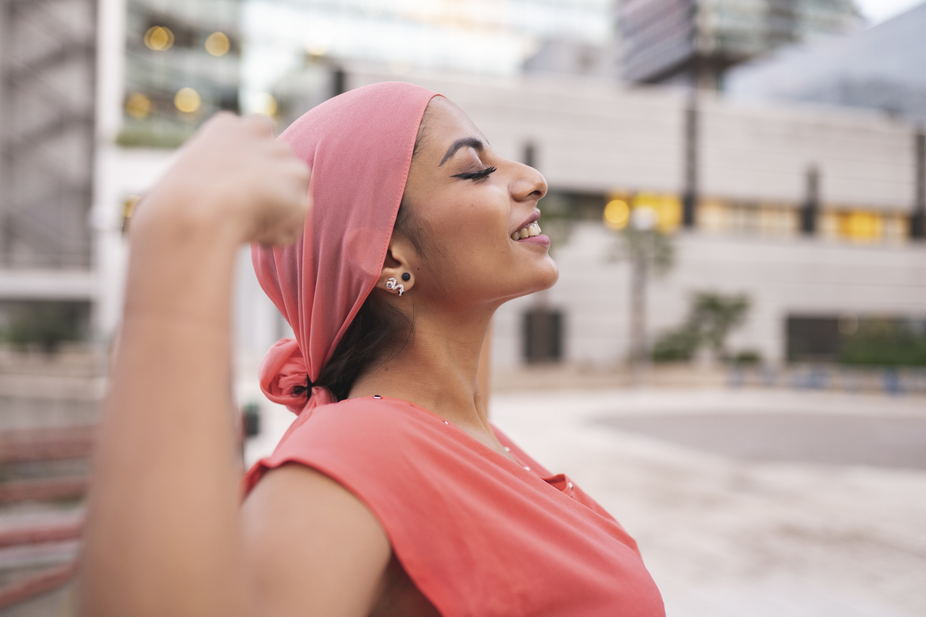 woman with raised arms showing muscle outdoors