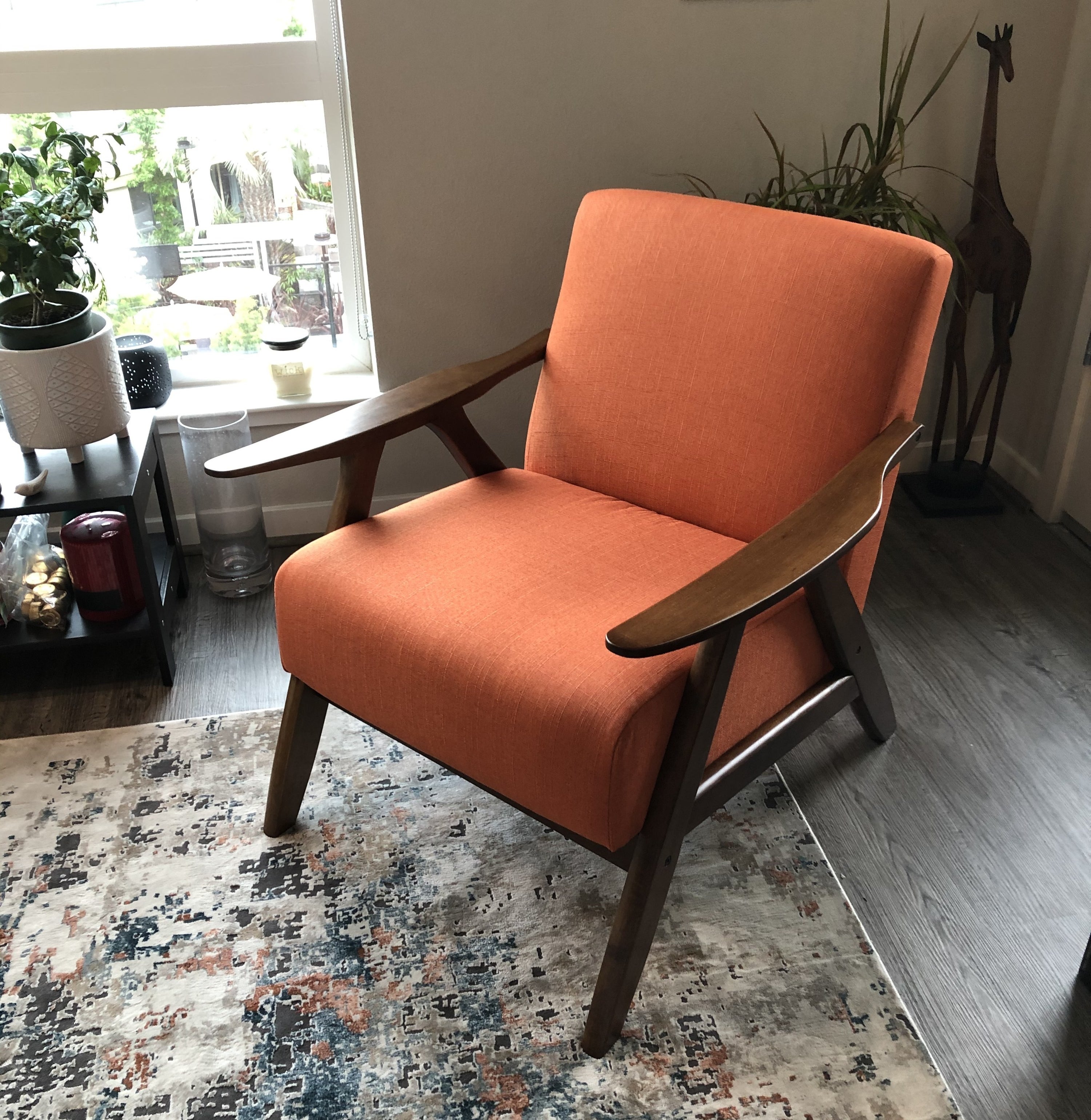 a reviewer photo of the orange chair in a living room