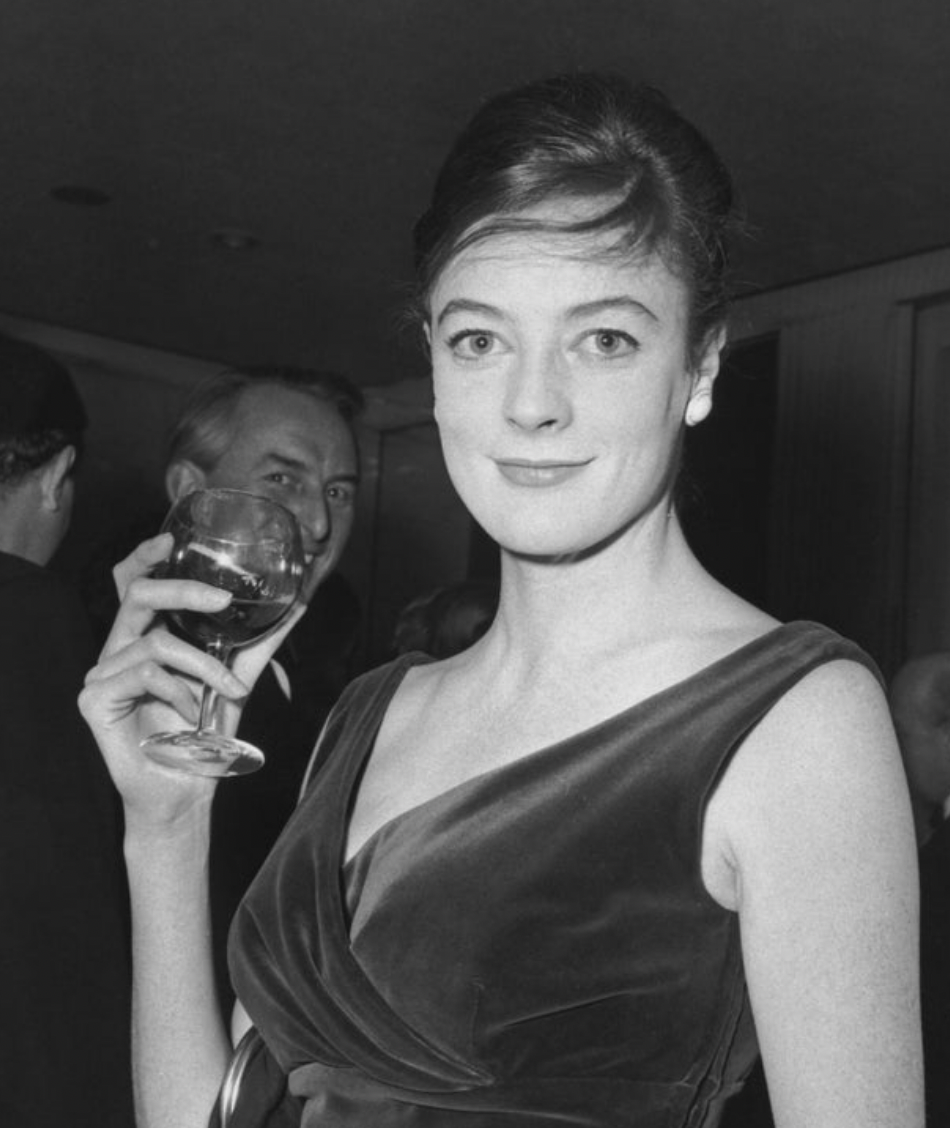 Young Maggie Smith in 1962 holding a glass of wine