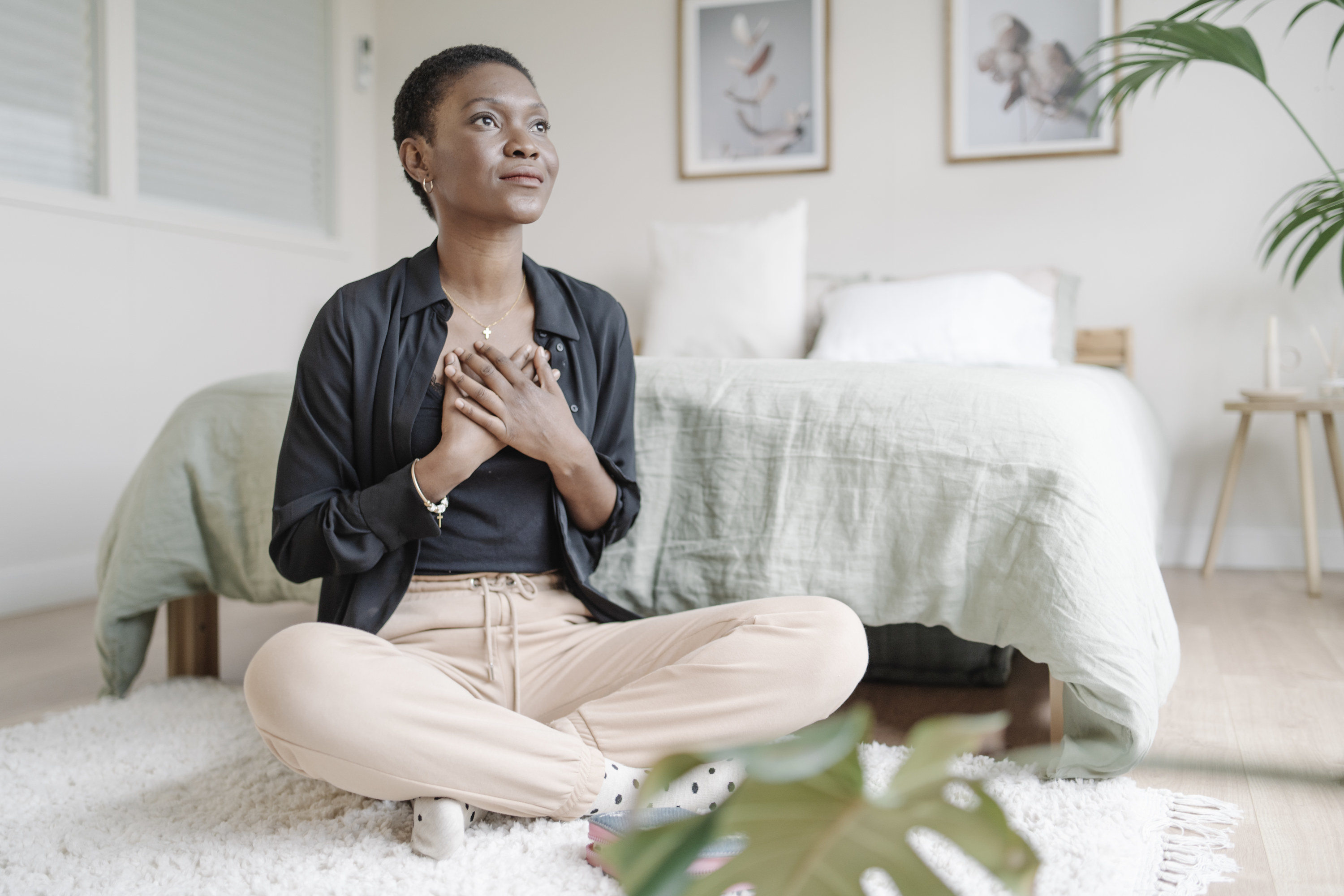 A woman in her room on the floor with her hands on top of her chest