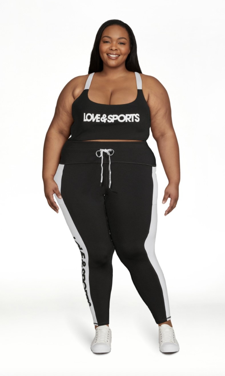 A person wearing a logo printed sports bra and matching leggings with white sneakers