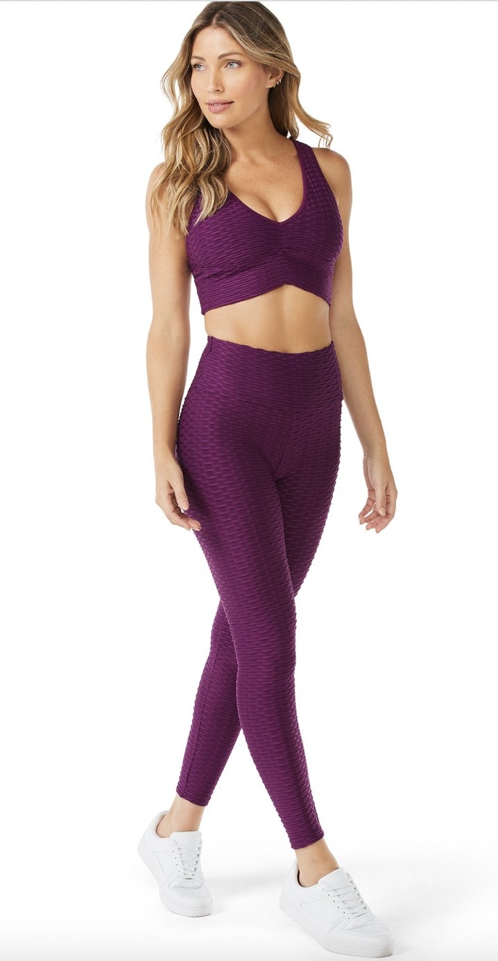 A person wearing a matching purple tank top and leggings set