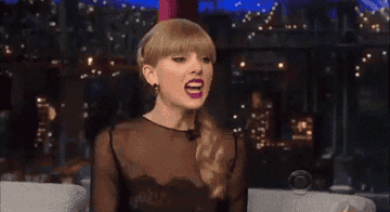 A GIF of Taylor Swift, reacting with hands in the air and her mouth open wide