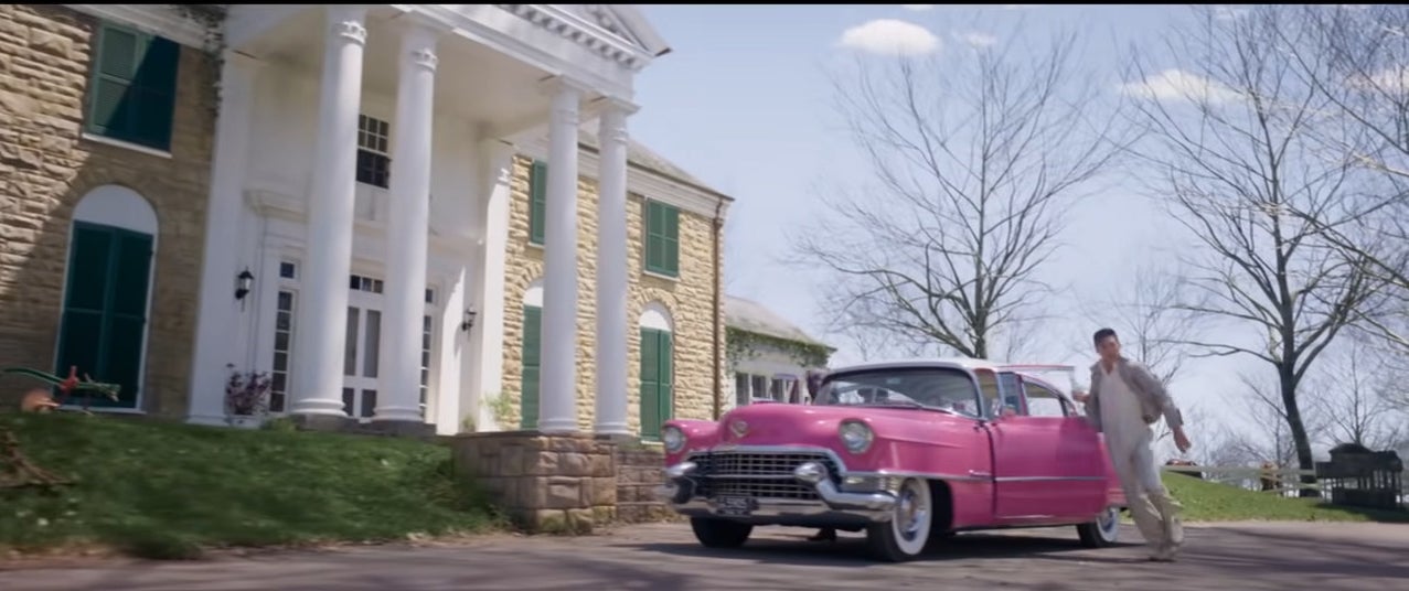 Pink cadillac parked outside of a large house with white pillars, graceland
