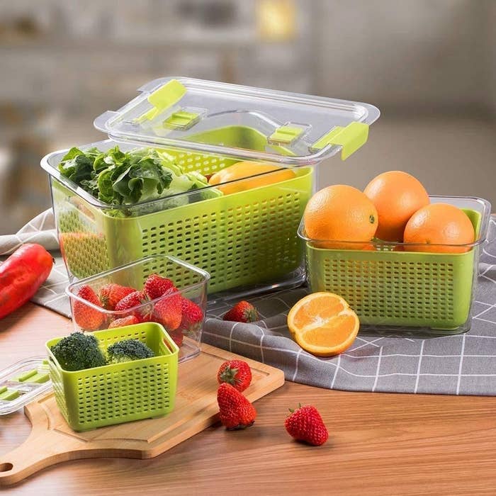 three of the containers filled with fruits and vegetables like strawberries and broccoli