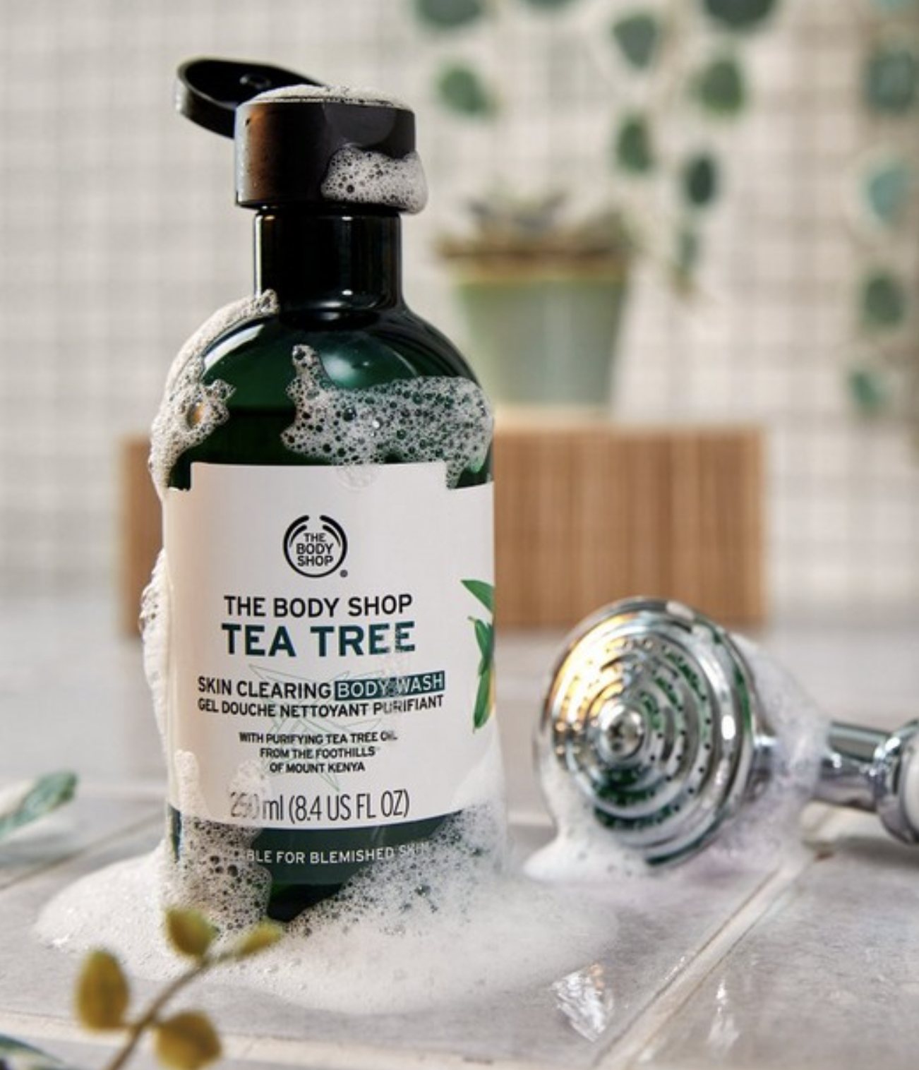 A sudsy bottle of tea tree oil body wash on a counter