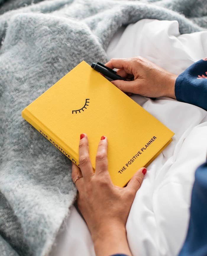 A person sitting under a blanket holding the positive planner