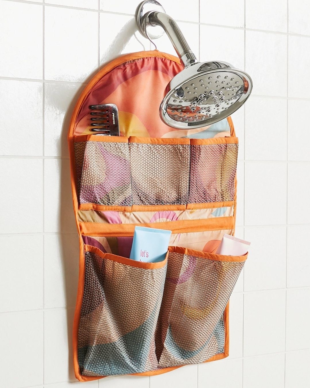 The caddy hanging from a shower head with products in its pockets