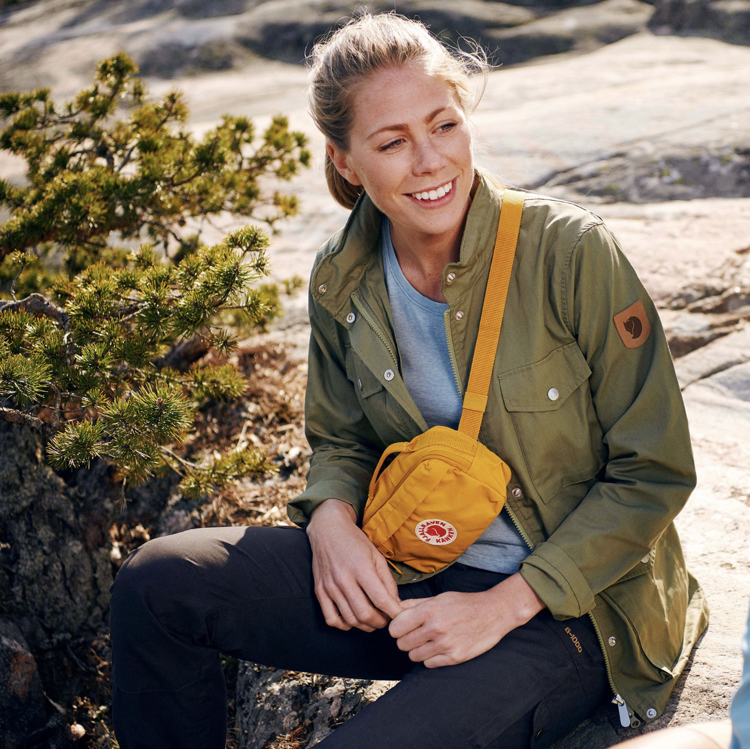 A person witting on a rock, wearing hiking gear and the hip pack