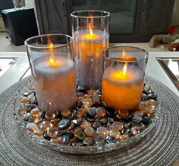 Reviewer image of three flameless candles in a glass dish filled with colorful pebbles