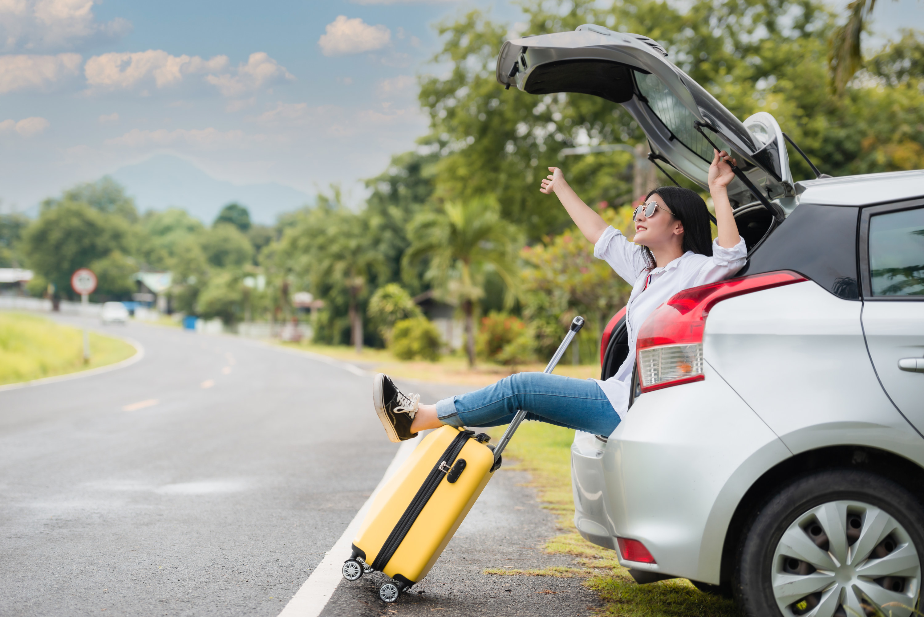 Woman sitting in the back of a rental car with a suitcase