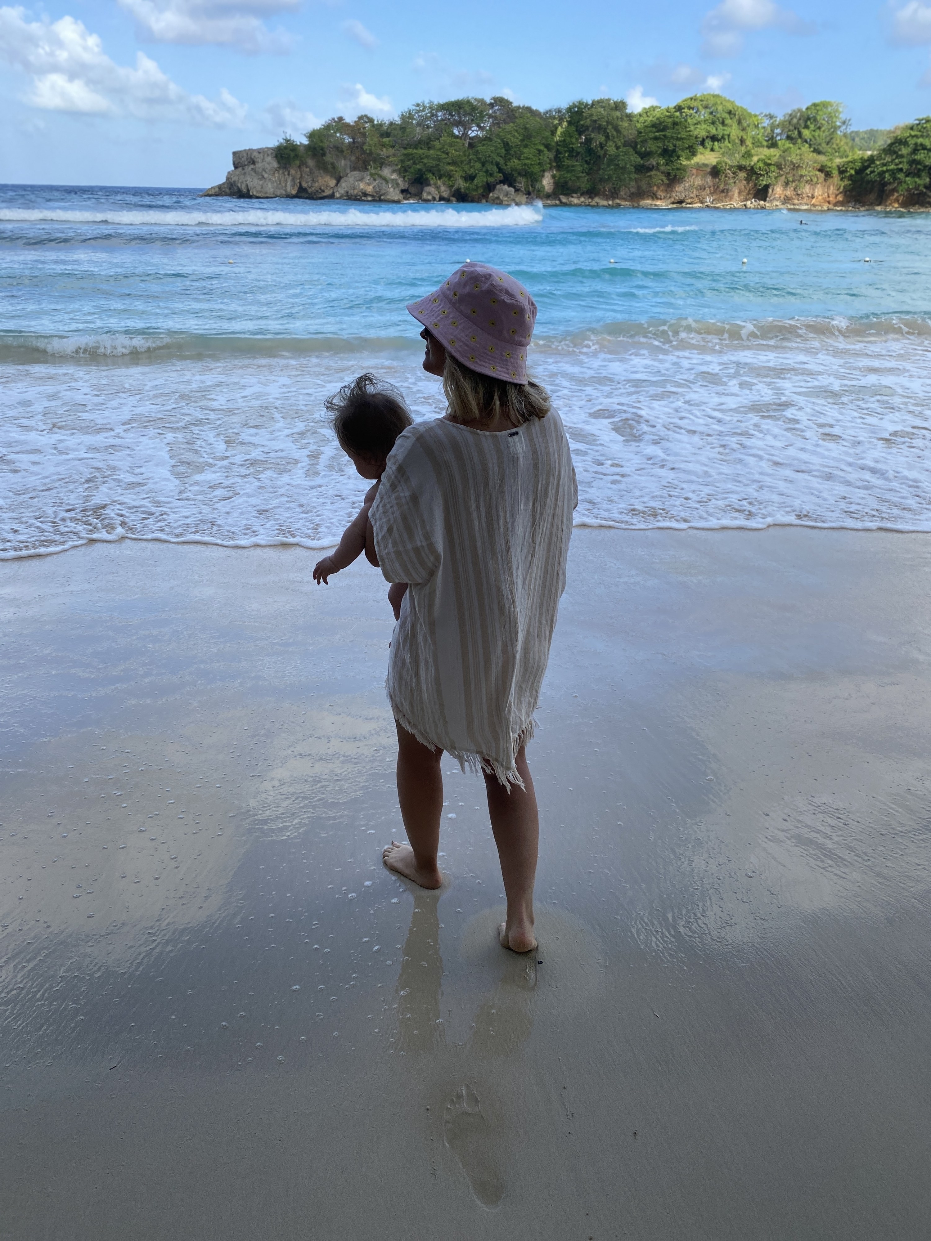 Woman walking on the beach with a baby