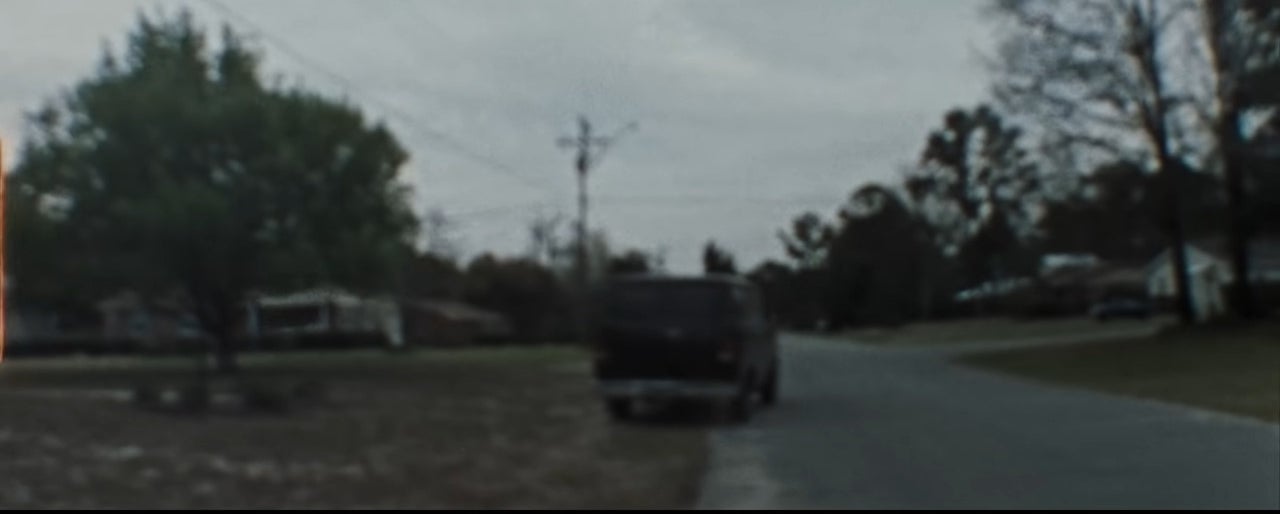 Vintage-looking footage of a black van driving down a road