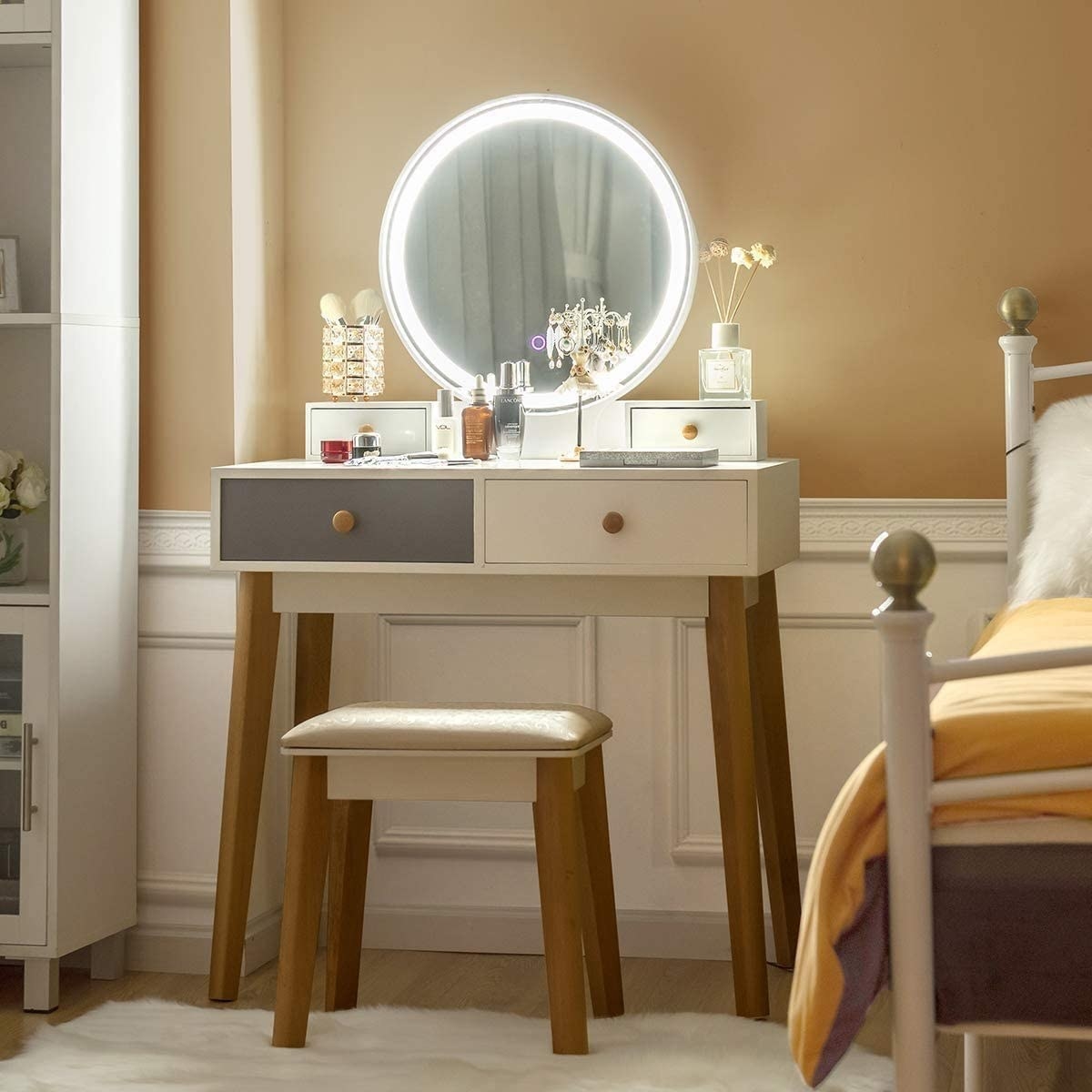 the vanity with stool with the light on next to a bed