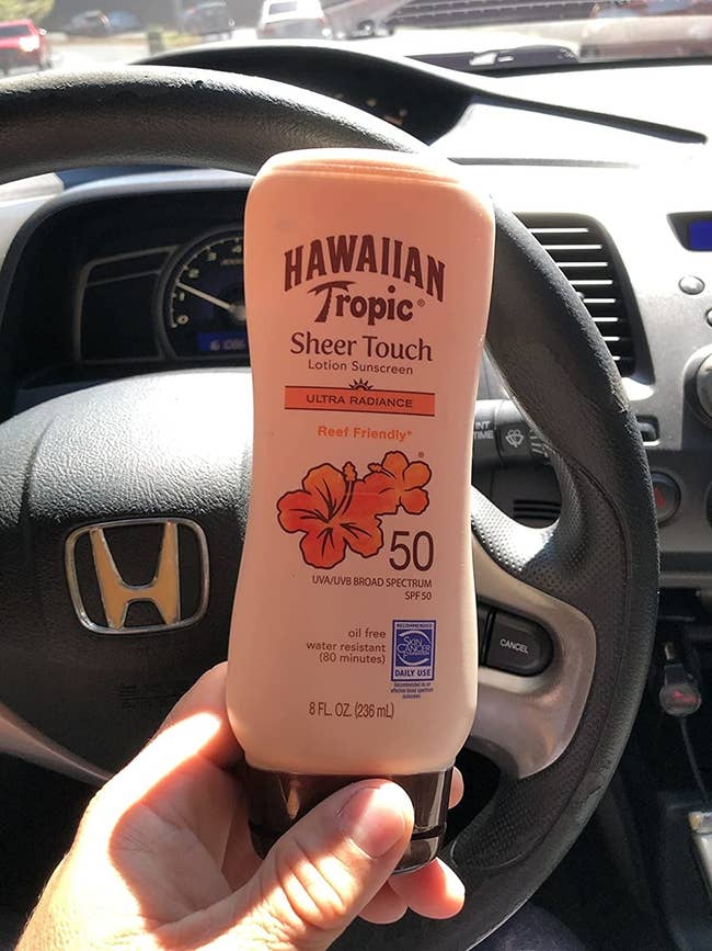 Reviewer holding Hawaiian Tropic Sheer Touch lotion sunscreen