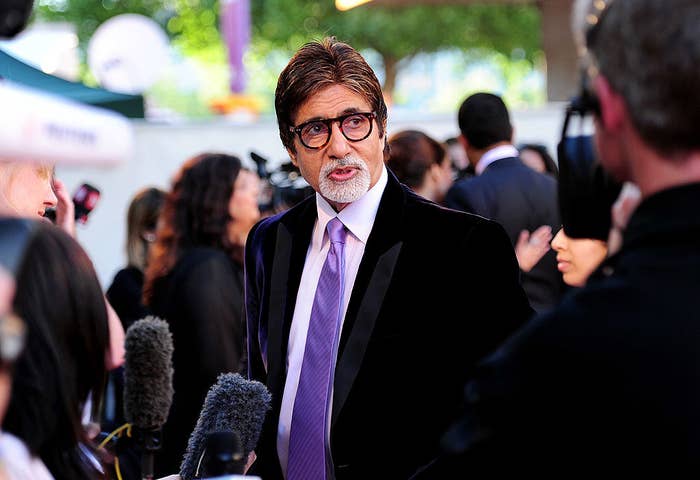 Amitabh Bachchan, wearing a suit and tie, speaks to the press