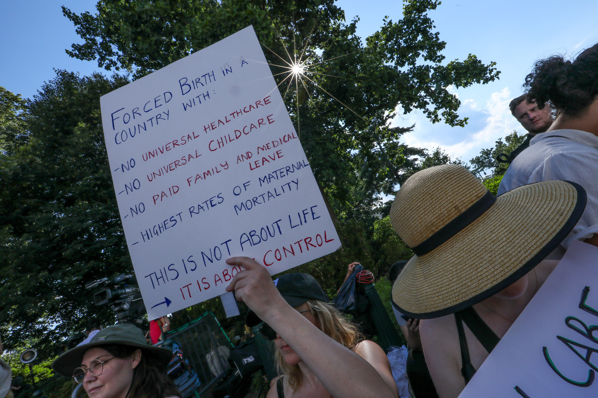 Someone holding a sign that says, &quot;Forced birth in a country with -no universal healthcare -no universal childcare -no paid family or medical leave -highest rates of maternal mortality. This is not about life. It is about control.&quot;