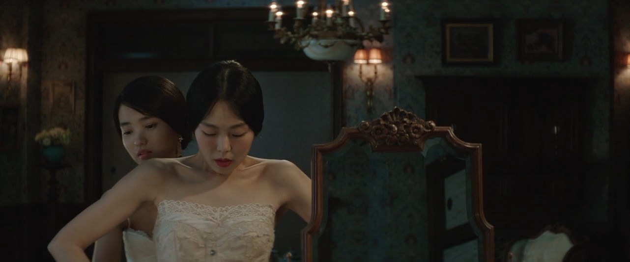 Sook-Hee (Kim Tae-ri) helping Hideko (Kim Min-hee) tie her corset from behind