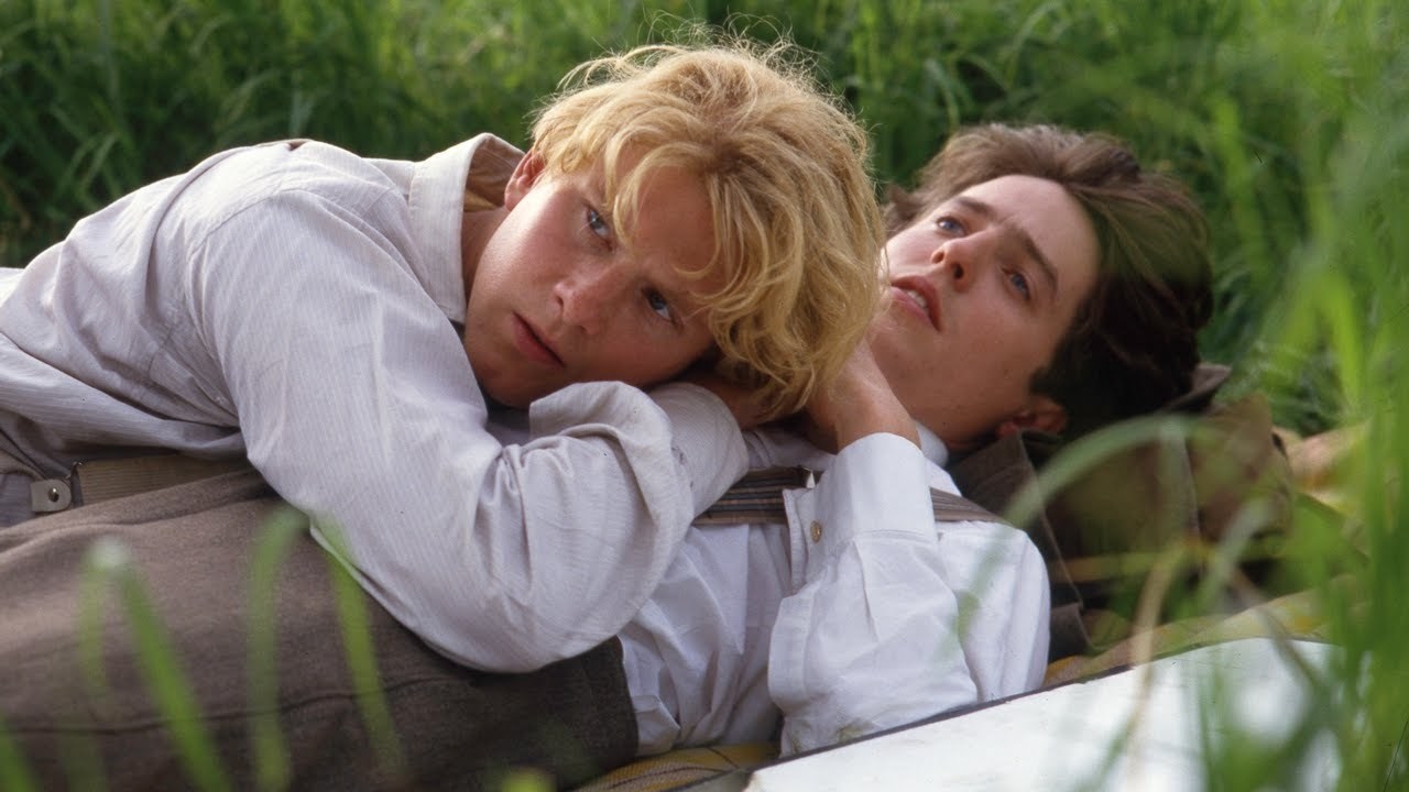 Clive (Hugh Grant) lying on the grass with Maurice (James Wilby) resting his head on his chest