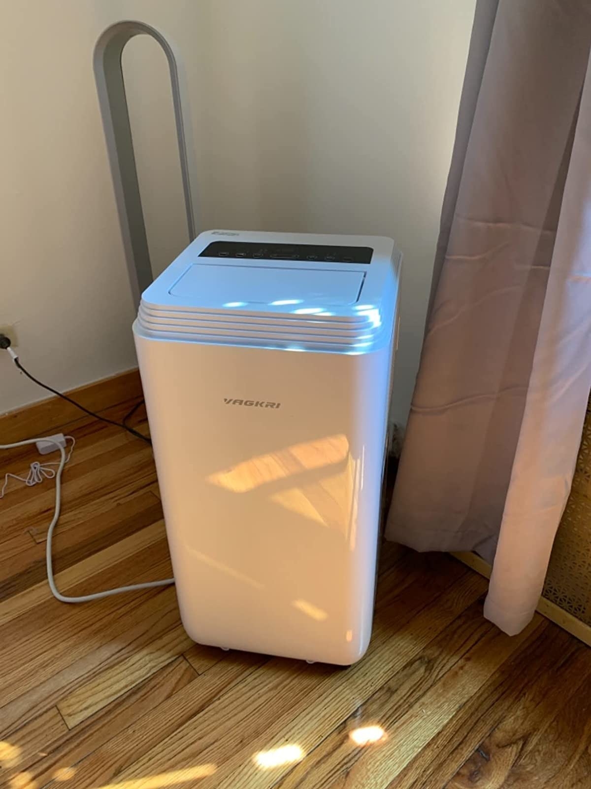 reviewer&#x27;s photo of the portable ac unit plugged into outlet by window