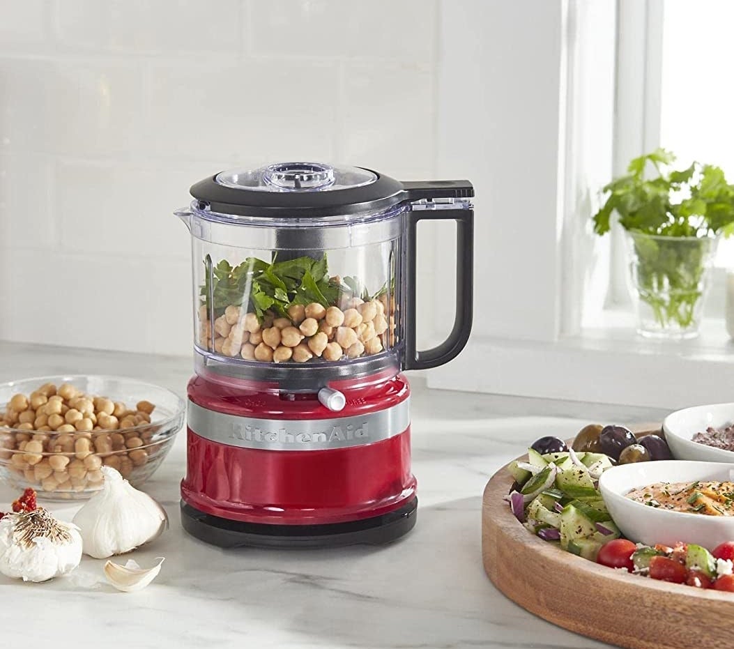 a petite food processor next to a bowl of chickpeas and olives