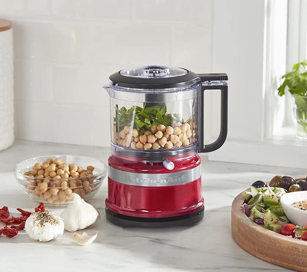 a petite food processor next to a bowl of chickpeas and olives