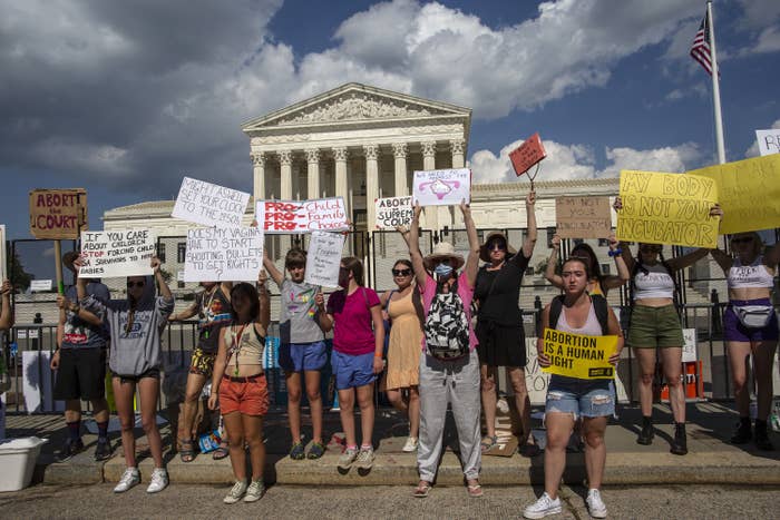 People standing outside the Supreme Court holding signs, including &quot;Abortion is a human right&quot;